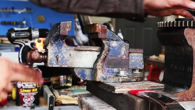 Man tightening a vice outside in his workshop