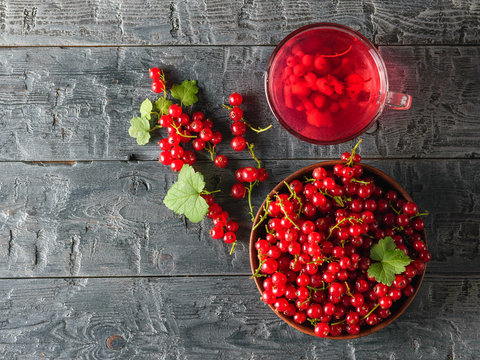 A large harvest of red currants and a refreshing drink on a wooden table. The view from the top. Flat lay.