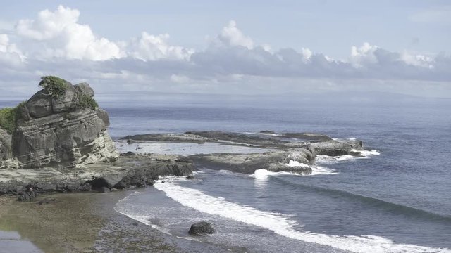 Waves meet the shoreline on a clear day in one of the islands at Biri, Samar, Philippines. Fishermen walk to the water in the distance.