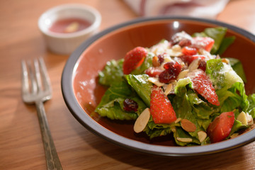 Fresh salad with lettuce and strawberries on table