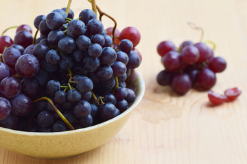 grape in bowl isolated on wood table background with copy space