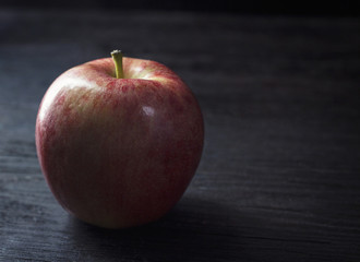 Apple in shadows on a wood table