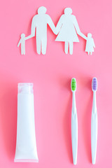 Teeth care, dental care. Set of toothbrushes and tooth paste near family silhouette on pink background top view