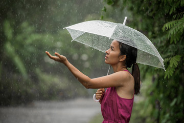 Beautiful young woman so sad as she holds out her palm to catch raining