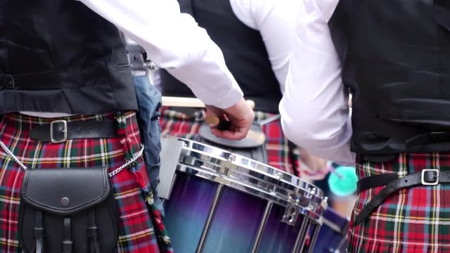 CLOSE UP. A men in a Scottish kilts play the drums. Footage in real time.