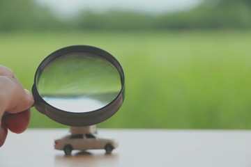 Magnifying Glass with miniature car searching for rent car.