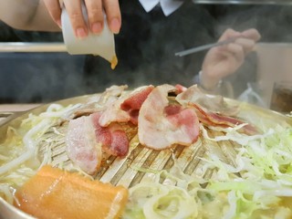 Close up of grilled fresh pork sliced on a hot pan, Woman hand use chopsticks holding korean pork grilled at restaurant