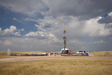 Crude oil exploration well site and drilling rig against a summer sky in the oil-rich Powder River Basin, Wyoming