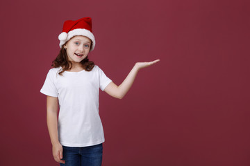 portrait of a smiling little girl in Santa hat on red background in Studio. Emotions. Christmas