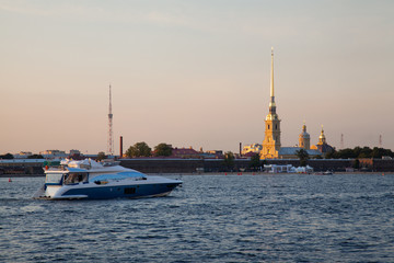 Fototapeta premium A yacht on the Neva river opposite the Peter and Paul fortress in Saint-Petersburg in the evening before sunset