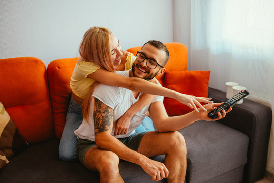 Positive young couple competing for TV remote at home
