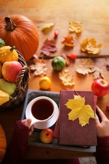 Autumn books.Autumn reading. book and tea,pumpkin, basket with apples, physalis, yellow maple leaves on a brown wooden table.Cozy autumn mood. Autumn time.Autumn season