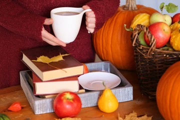 Obraz na płótnie Canvas Autumn books.Autumn reading. book and tea,pumpkin, basket with apples, physalis, yellow maple leaves on a brown wooden table.Cozy autumn mood. Autumn time.