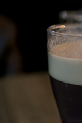 Edge glass with dark craft beer. Selective focus. Copy space. Dark background.