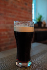 Glass of dark beer with foam.