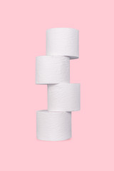 A stack of toilet paper rolls on pink color background.