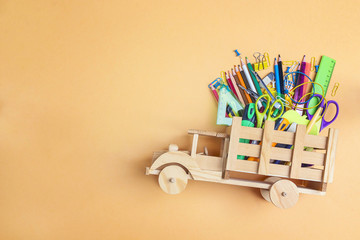 Back to school concept with wooden toy truck with school supplies on yellow background and copy...