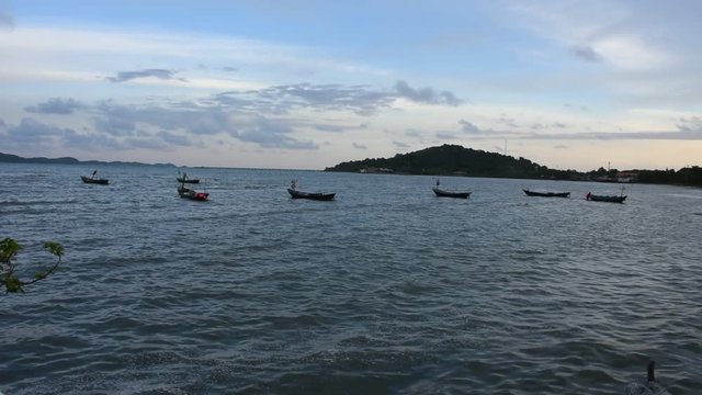 Wooden fishery boat floating and stop wait for go to catching fish in the sea in evening time at Ban Pae beach in Rayong, Thailand