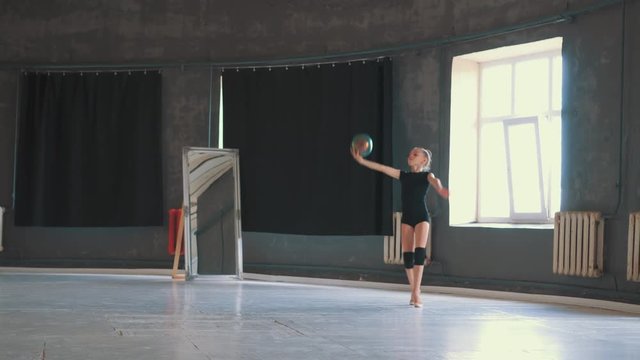 Gymnast girl performing rhythmic gymnastics element with ball