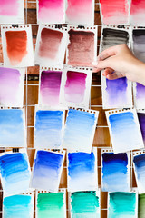 Naklejka premium watercolors swatch assortment background. ink dyes colors mix on paper. art painting and drawing. inspiration and creativity. artist skills practice. free space concept. woman hand choosing.