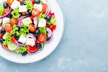 Greek salad of fresh cucumber, tomato, sweet pepper, lettuce, red onion, feta cheese and olives with olive oil