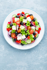 Greek salad of fresh cucumber, tomato, sweet pepper, lettuce, red onion, feta cheese and olives with olive oil