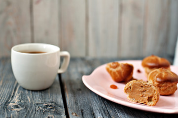 Cup of coffee, cakes and branch of a lilac on a gray wooden background