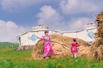 Mongolian mother and daughter working in front of the grass