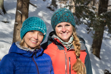 Pair of female friends snowshoeing in forest.