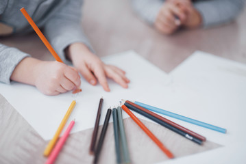 Children lie on the floor in pajamas and draw with pencils. Cute child painting by pencils.Hand of...
