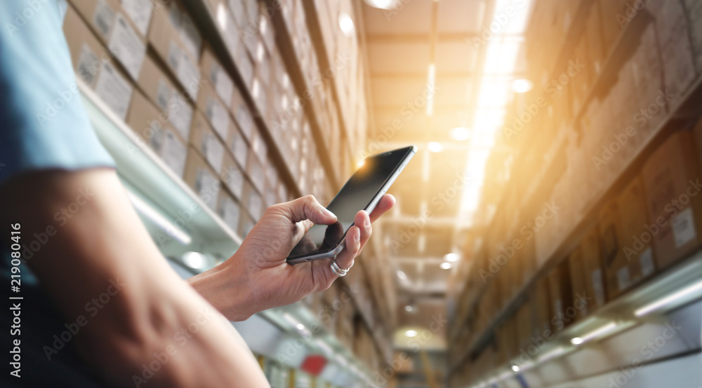 Poster Factory worker using application on mobile smartphone to operate automation for modern trade. Checking order in large warehouse. Import and export the shipping cargo. Business marketing and technology