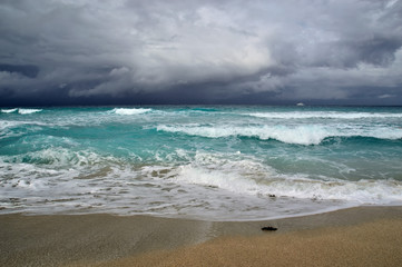 coast of the Atlantic Ocean during a storm, waves on the sand, motor yacht on the horizon, low clouds, Varadero, Cuba