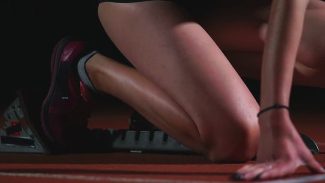 Professional woman athlete on a dark background gotovtes to run the sprint of Jogging shoes in sneakers on the track of the stadium on a dark background. Close up