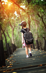 a little girl walks alone on the old wooden bridge in the jungle rainforest, feel wander, stray and...