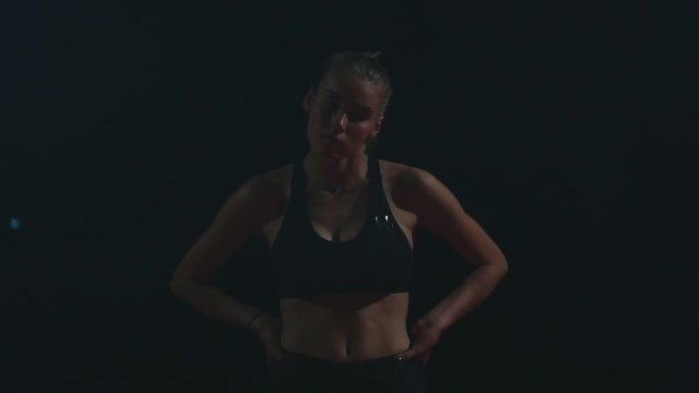 Professional woman athlete on a dark background gotovtes to run the sprint of Jogging shoes in sneakers on the track of the stadium on a dark background. Average plan