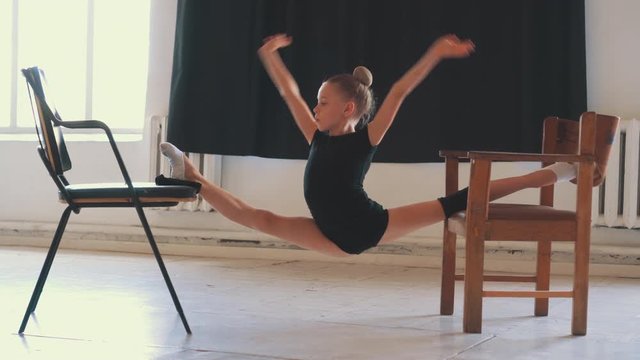Fit gymnast doing straddle split between two chairs