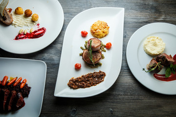 wooden table topped with white plates with different types of food in restaurant
