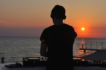 DJ plays music on the beach at sunset