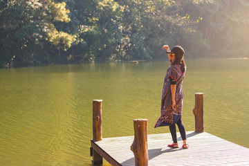 Asian woman standing alone on wooden bridge in front lake ,Thailand