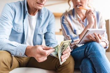 cropped shot of elderly couple counting money and taking notes during relocation