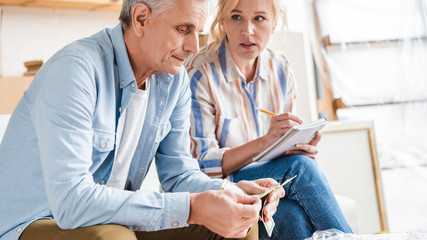 serious senior couple counting money and taking notes during relocation