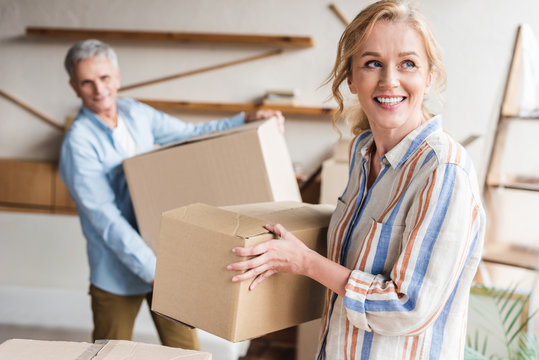 Happy Elderly Couple Holding Cardboard Boxes While Moving Home