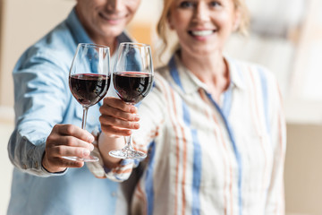 cropped shot of happy elderly couple holding glasses of wine