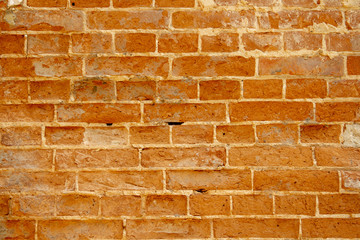 Fototapeta premium Chipped red brick in an ancient wall during the restoration. Restoration of plaster and whitewashed brick wall of the 1600s. Restoration of plaster of an ancient brick wall by masters-restorers.