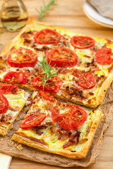 Puff pastry tart pizza style with tomatoes, courgette, and bacon