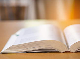 Close-up of open book on desk with sun light effect blur background.