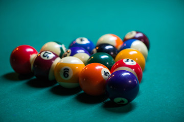 Sport billiard balls set arranged in shape of triangle on green billiard table in pub. Players are ready for the first hit of the round to start the billiard game