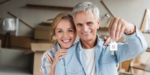 happy senior couple holding keys from new apartment and smiling at camera