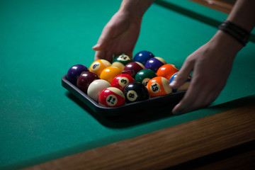 Sport billiard balls set and a chalk in a box on green billiard table in pub. Players are ready for...