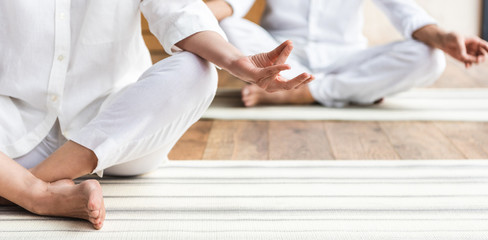 cropped shot of elderly couple sitting in lotus position and practicing yoga together